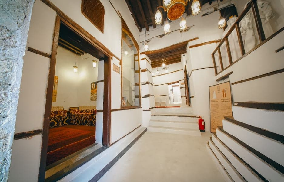 An interior corridor with white walls and wooden shelves in Beit Al-Matbouli
