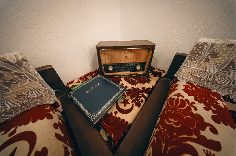 An old radio and a Qur'an on a table between the majlis seats