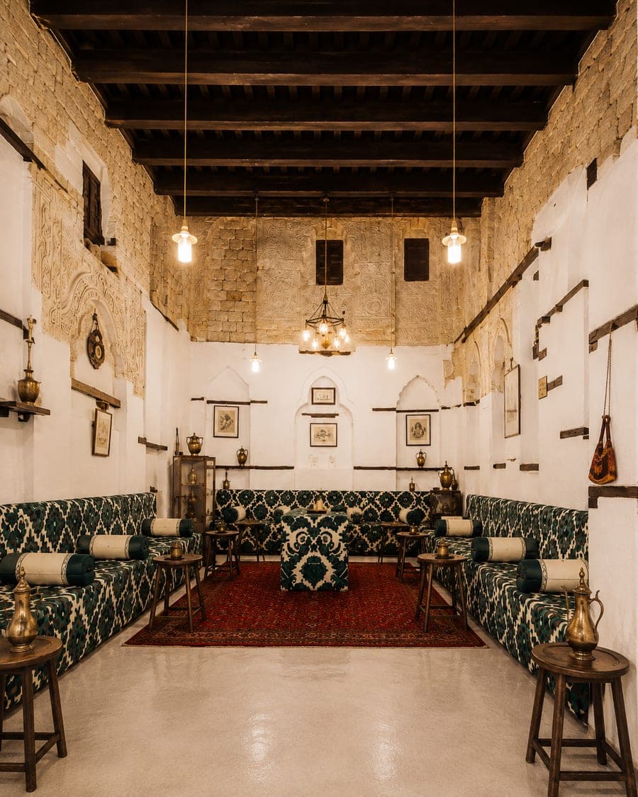 The Diwan: a spacious majlis with stone walls, a wooden ceiling and patterned green seating